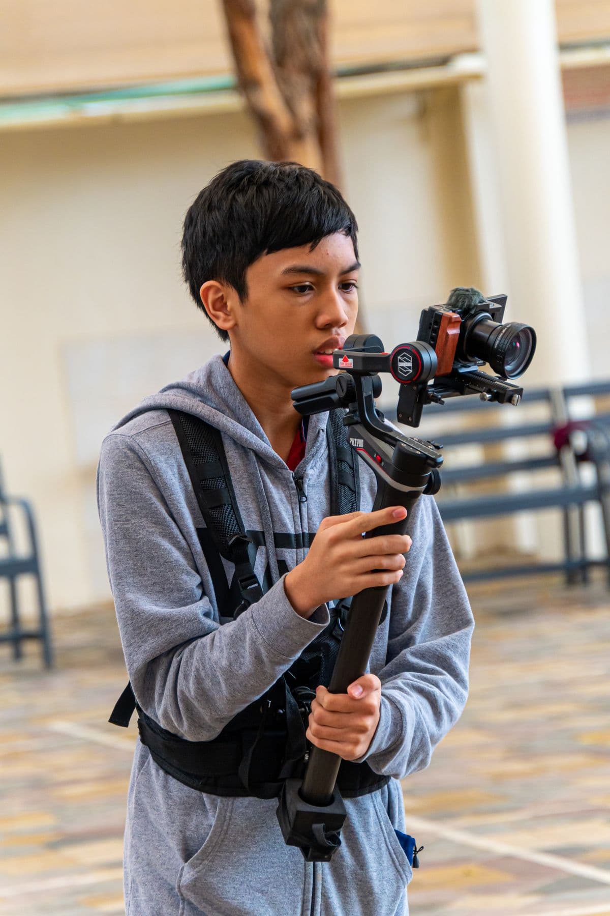 A teenager filming outdoors with a camera mounted on a stabiliser