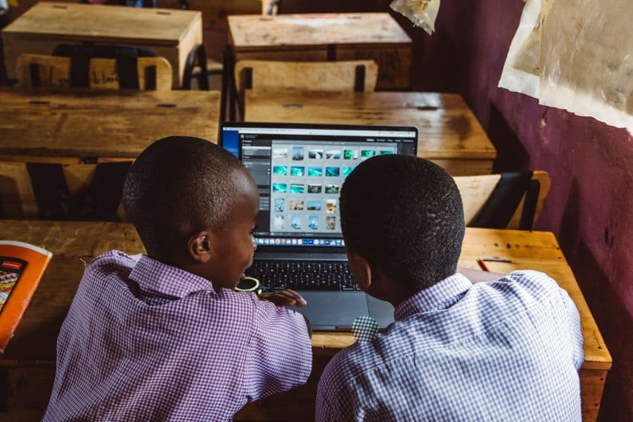 Two students in school uniform working together on a laptop