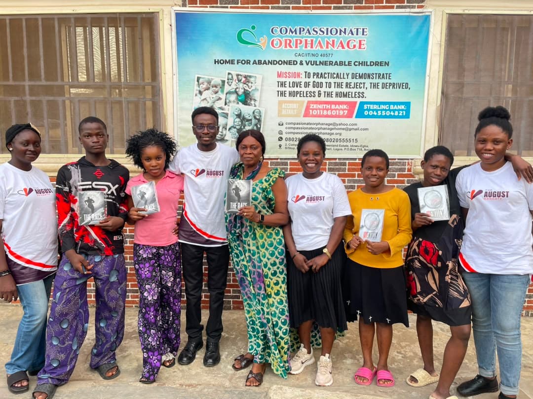 Team members and children holding copies of books presented during an orphanage visit